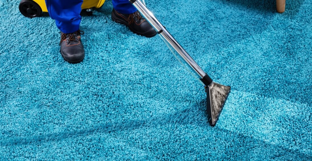 Professional cleaner using a carpet cleaning machine to deep clean a bright blue shag rug.