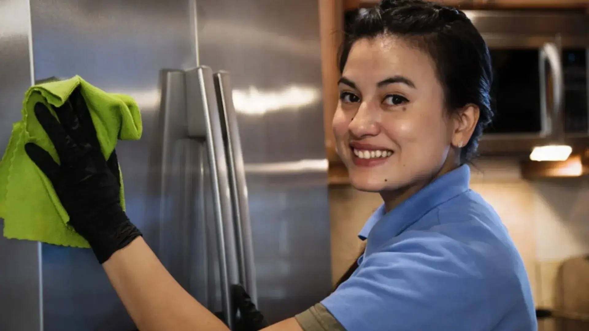 Professional cleaner wiping a refrigerator during house cleaning services in Tri-Cities
